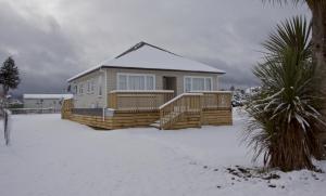une maison avec une véranda enneigée dans la neige dans l'établissement The Mountain Pad - Rangataua Holiday Home, à Ohakune