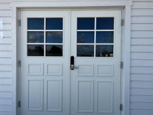 uma porta de garagem branca com duas janelas numa casa em Hallands Equestrian Center em Laholm