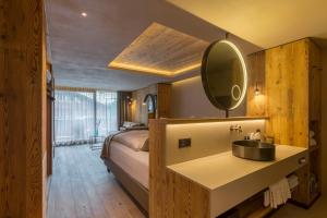 a bedroom with a bed and a sink and a mirror at Hotel Bellerive in Zermatt