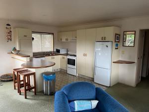 una cucina con divano, tavolo e frigorifero di Baskervilla - Whangamata Holiday Home a Whangamata