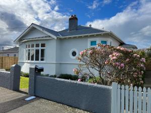 a white house with a fence in front of it at Luxurious Home Close to Beach in Dunedin