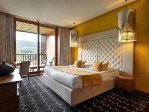a bedroom with a large bed and a balcony at Hotel Balnea Superior - Terme Krka in Dolenjske Toplice