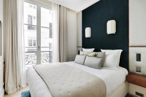 una camera da letto con un letto grande e una grande finestra di TheLander - Serviced Apartments in Louvre - Rivoli a Parigi