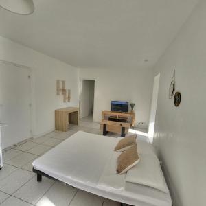 Jest to biały pokój z łóżkiem i biurkiem. w obiekcie Bel appartement avec jardin de 30m2 , climatisé avec parking et arrivée autonome w mieście Cabestany
