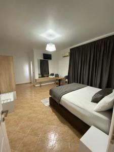 Dormitorio con cama, escritorio y TV en Monte Rei Hotel en Lushnjë