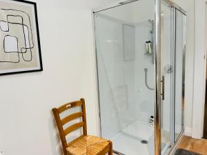 y baño con ducha de cristal y silla de madera. en Luxurious Home Close to Beach en Dunedin