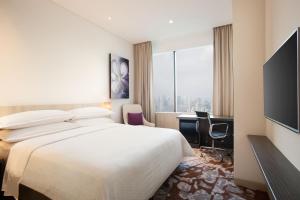 um quarto de hotel com uma cama, uma escrivaninha e uma janela em Four Points by Sheraton Jakarta Thamrin em Jacarta