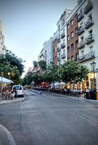 una calle urbana vacía con mesas, sillas y edificios en Habitacion Centro De Madrid, en Madrid