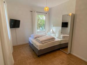 1 dormitorio con cama con espejo y ventana en Villa Pewsum en Krummhörn