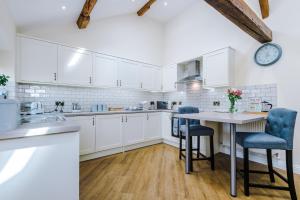 a kitchen with white cabinets and a table and chairs at Tranquil 1-bed barn in Beeston by 53 Degrees Property, ideal for Couples & Friends, Great Location - Sleeps 2 in Beeston