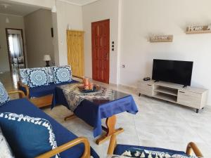 een woonkamer met blauwe meubels en een televisie bij Voulas Guest House in Volos