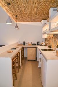a kitchen with white counters and a wooden ceiling at Mylopetra Milos Suites in Tripití