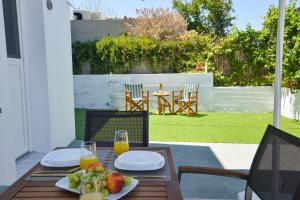 a wooden table with plates of fruit and orange juice at Mylopetra Milos Suites in Tripiti +13 photos