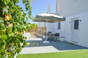 a patio with an umbrella and a table and chairs at Mylopetra Milos Suites in Tripití