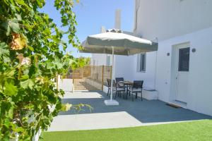 a patio with an umbrella and a table and chairs at Mylopetra Milos Suites in Tripiti