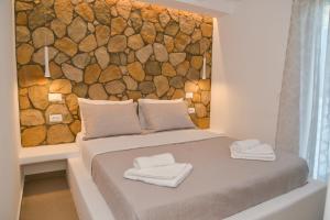 Una cama con dos toallas encima. en Mylopetra Milos Suites en Tripití