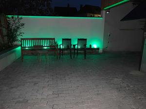 two benches and a table with green lights at Hotel Garni Pension Ruth in Mutterstadt