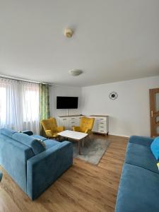 ein Wohnzimmer mit einem blauen Sofa und gelben Stühlen in der Unterkunft Al-Dom Apartamenty Olymp 204 in Kołobrzeg