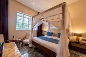 a bedroom with a canopy bed and a window at Muthu Sovereign Suites & Spa, Limuru Road, Nairobi in Limuru