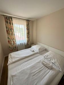 1 Schlafzimmer mit 2 Betten mit weißer Bettwäsche und einem Fenster in der Unterkunft Al-Dom Apartamenty Olymp 204 in Kołobrzeg