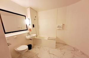 a white bathroom with a toilet and a sink at Crystal Hotel Saint Denis Basilique in Saint-Denis