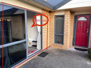 a red door on the side of a brick house at Sunny self checkin studio with private entry& ensuite&heat pump in Hamilton