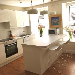 a kitchen with white cabinets and a kitchen island with stools at Berlin Wall Apartment at The Residence Bantry in Bantry