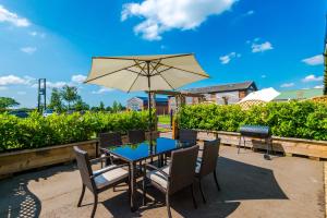 a patio with a table and chairs and an umbrella at Luxurious 3-bed barn in Beeston by 53 Degrees Property, ideal for Families & Groups, Great Location - Sleeps 6 in Beeston