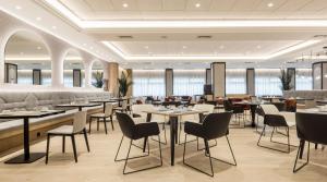 a restaurant with tables and chairs and windows at Ilunion Alcora Sevilla in San Juan de Aznalfarache