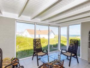eine abgeschirmte Veranda mit einem Glastisch und Stühlen in der Unterkunft Holiday Home Sandnæshagevej II in Lild Strand