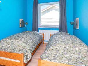 2 Betten in einem Zimmer mit blauen Wänden und einem Fenster in der Unterkunft Holiday Home Sandnæshagevej II in Lild Strand