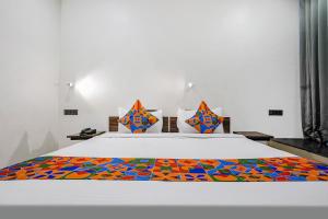 a bedroom with a white bed with a colorful blanket at FabHotel Lotus I in Surat
