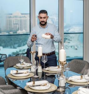 a man standing in front of a table with a cell phone at Manzil - Stylish 3BR in Palm w Private Beach & Sea View in Dubai