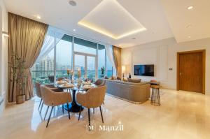 un soggiorno con tavolo e divano di Manzil - Stylish 3BR in Palm w Private Beach & Sea View a Dubai