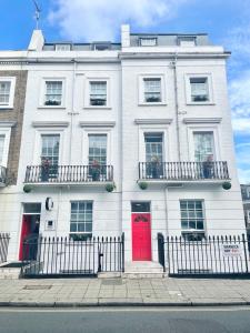 a white building with red doors on a street at Enrico Hotel in London