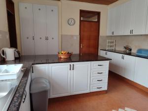 a kitchen with white cabinets and a bowl of fruit on the counter at Lantana Gardens B2 & B8 Apartment in Nairobi