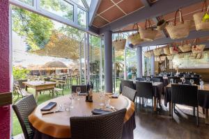 un restaurante con mesas, sillas y ventanas grandes en Hôtel-Restaurant Logis l'Aubrac Laguiole, en Laguiole