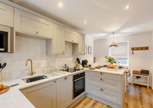a kitchen with white cabinets and a sink at Ty Fin in Llanbedrog
