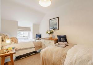 a bedroom with two beds and a dresser and a window at Ty Fin in Llanbedrog