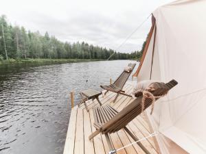 um grupo de cadeiras em um barco em um rio em Långforsen Glamping & Lapland Experience 