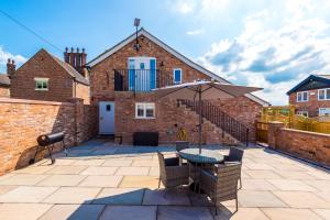 a patio with a table and an umbrella at Unique 2-bed barn in Beeston by 53 Degrees Property, ideal for Families & Friends, Great Location - Sleeps 4 in Beeston