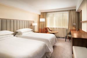 a hotel room with two beds and a desk at Sheraton Zagreb Hotel in Zagreb