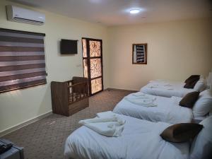 una camera con tre letti con asciugamani di Petra Hill a Wadi Musa