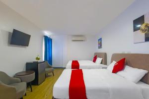 マニラにあるOYO 937 Loveness Apartelleのベッド2台とテレビが備わるホテルルームです。