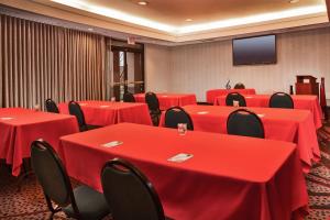 a conference room with red tables and chairs and a flat screen tv at Courtyard by Marriott Dulles Town Center in Sterling