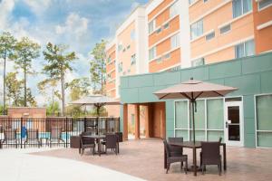 an outdoor patio with tables and chairs and umbrellas at Courtyard by Marriott Houston City Place in Spring