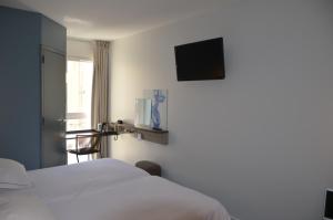 a hotel room with a bed and a tv on the wall at Kyriad Metz Centre - Restaurant Moze in Metz