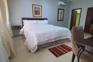 una camera con un grande letto bianco e una scrivania di Zion Residence 5-Star 4-Bedroom Terrace House ad Abuja