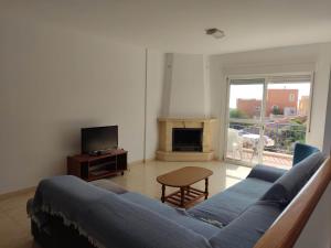 sala de estar con sofá azul y TV en Villas Montemar, en San José
