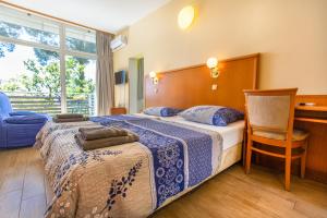 ein Schlafzimmer mit einem Bett, einem Stuhl und einem Fenster in der Unterkunft Maestral Residence in Portorož